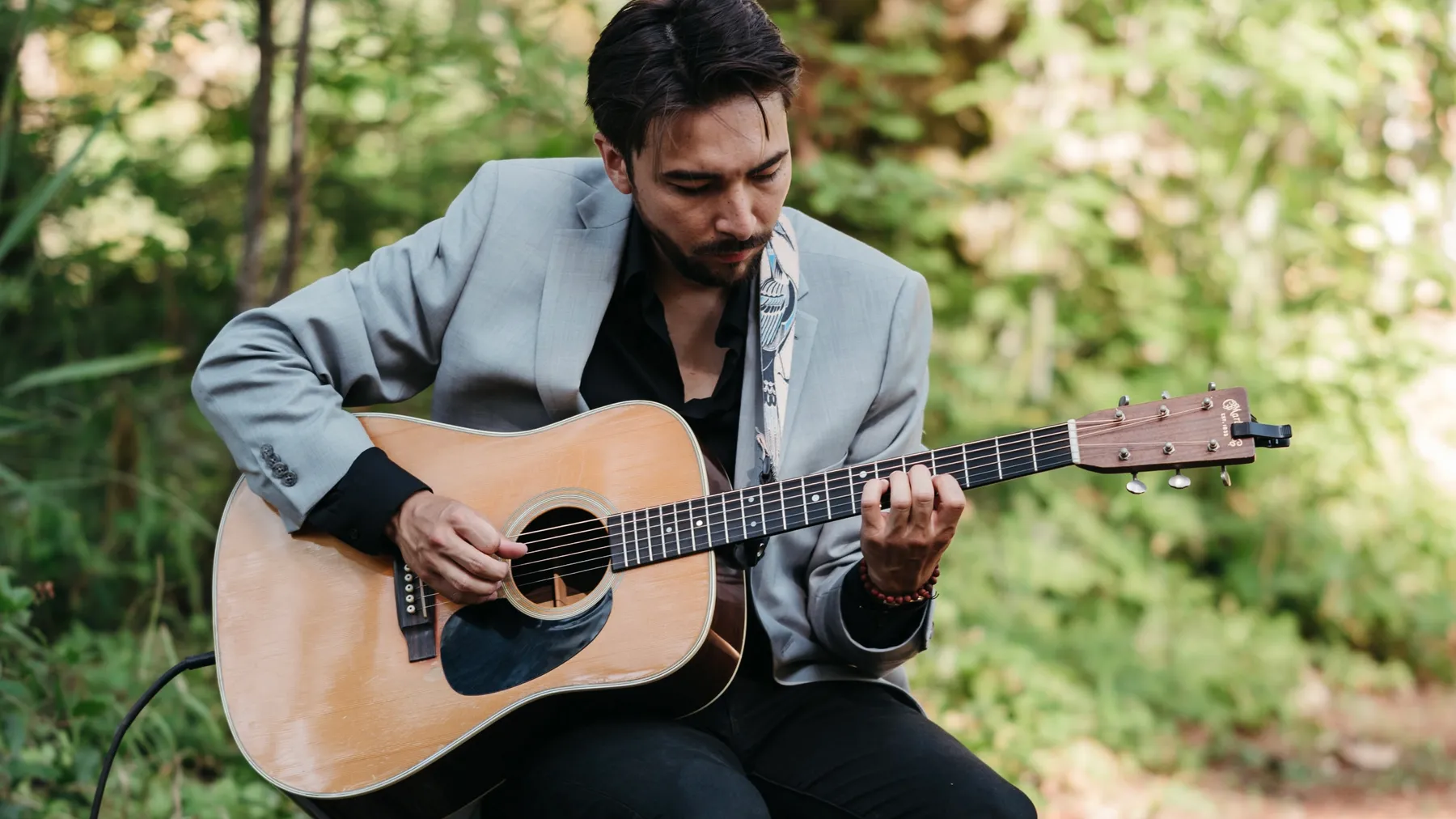 Alex Nishi playing acoustic guitar outdoors